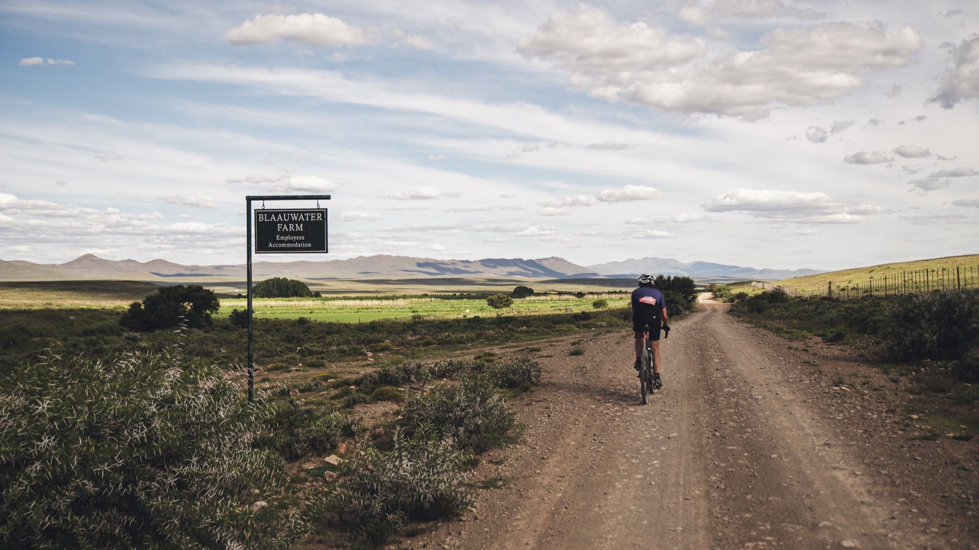 A rider passing the Blaauwater Farm sign on a gravel road