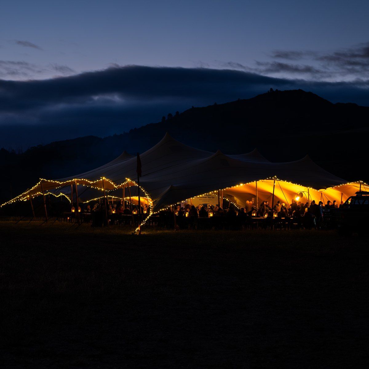 The lit stretch-tent bomas of a Burn Camp at nightfall