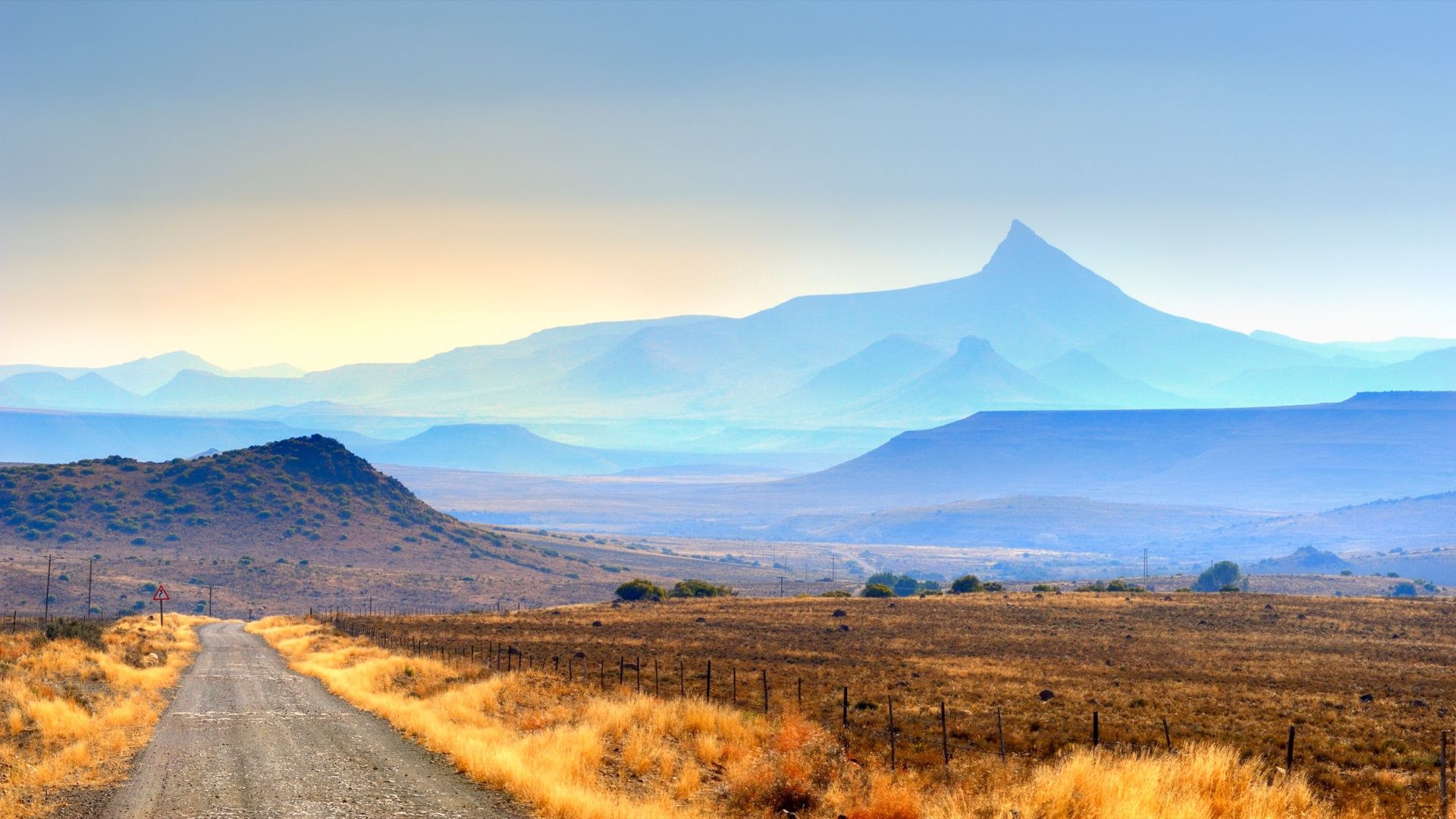 Compassberg’s peak rising above the Sneeuberg, with a gravel road through golden grass below