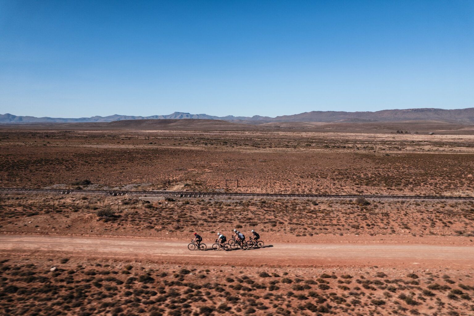 A small group of riders on a gravel road across the open Karoo plains