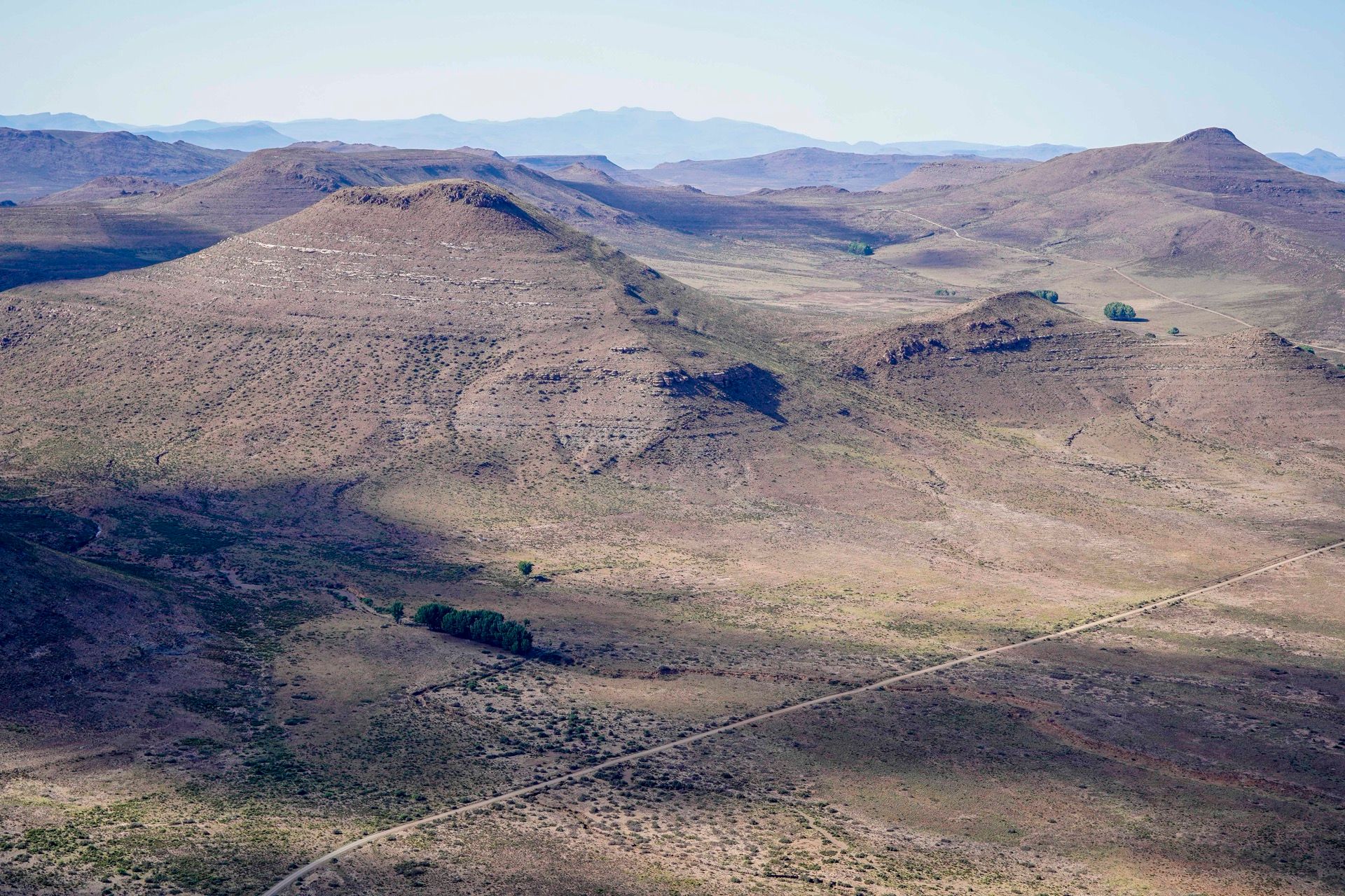 Late light over the folded ridges of the Karoo, with a gravel road winding between them