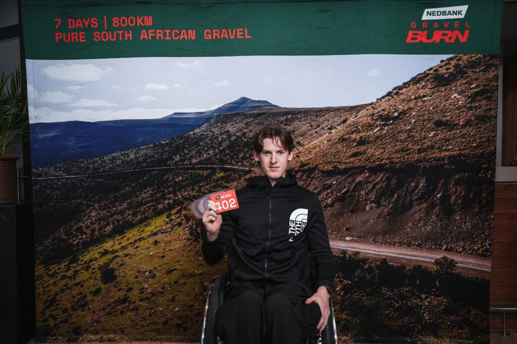 Bryce Carter in his wheelchair at registration for the first Nedbank Gravel Burn, holding his race number